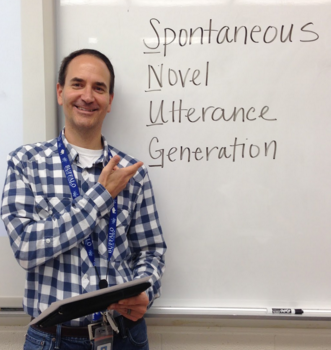 Chris standing in front of a whiteboard with the words Spontaneous Novel Utterance Generation written on it.